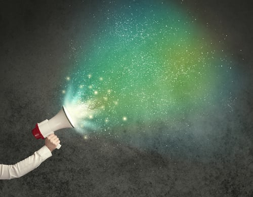 Person holding a megaphone releasing colorful sound waves or particles, symbolizing noise .