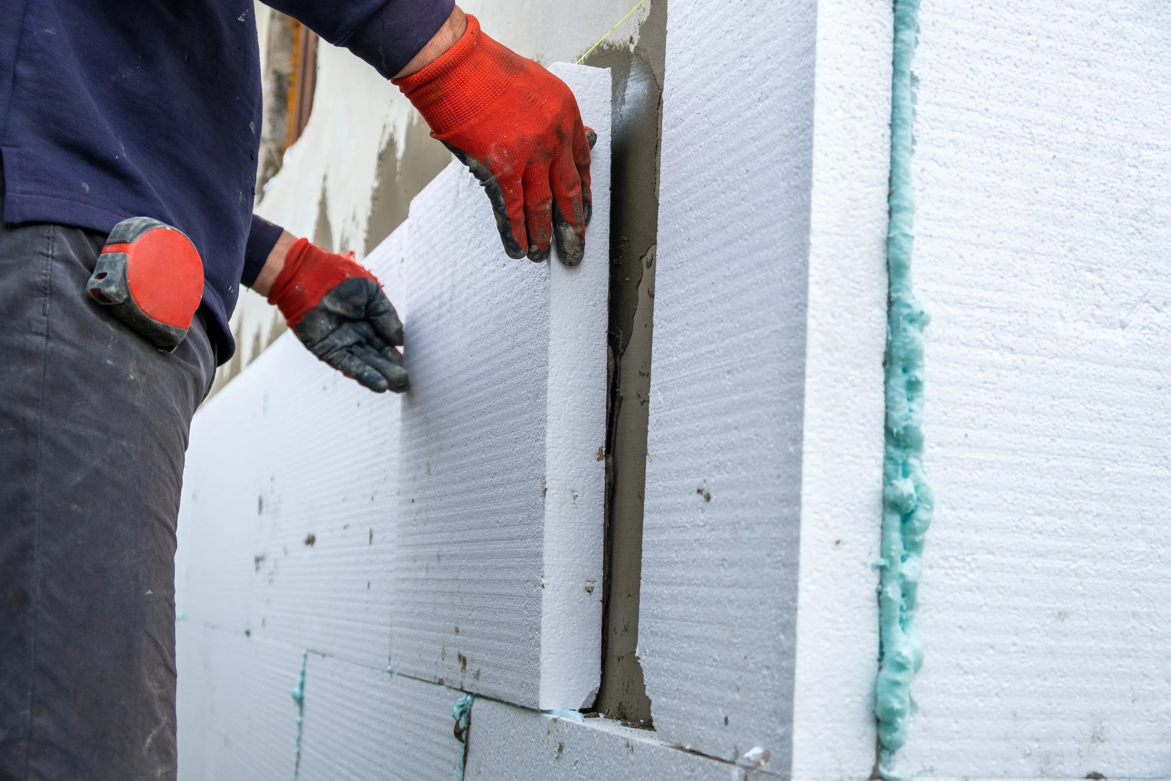 Construction worker installing EPS foam board insulation on an exterior wall