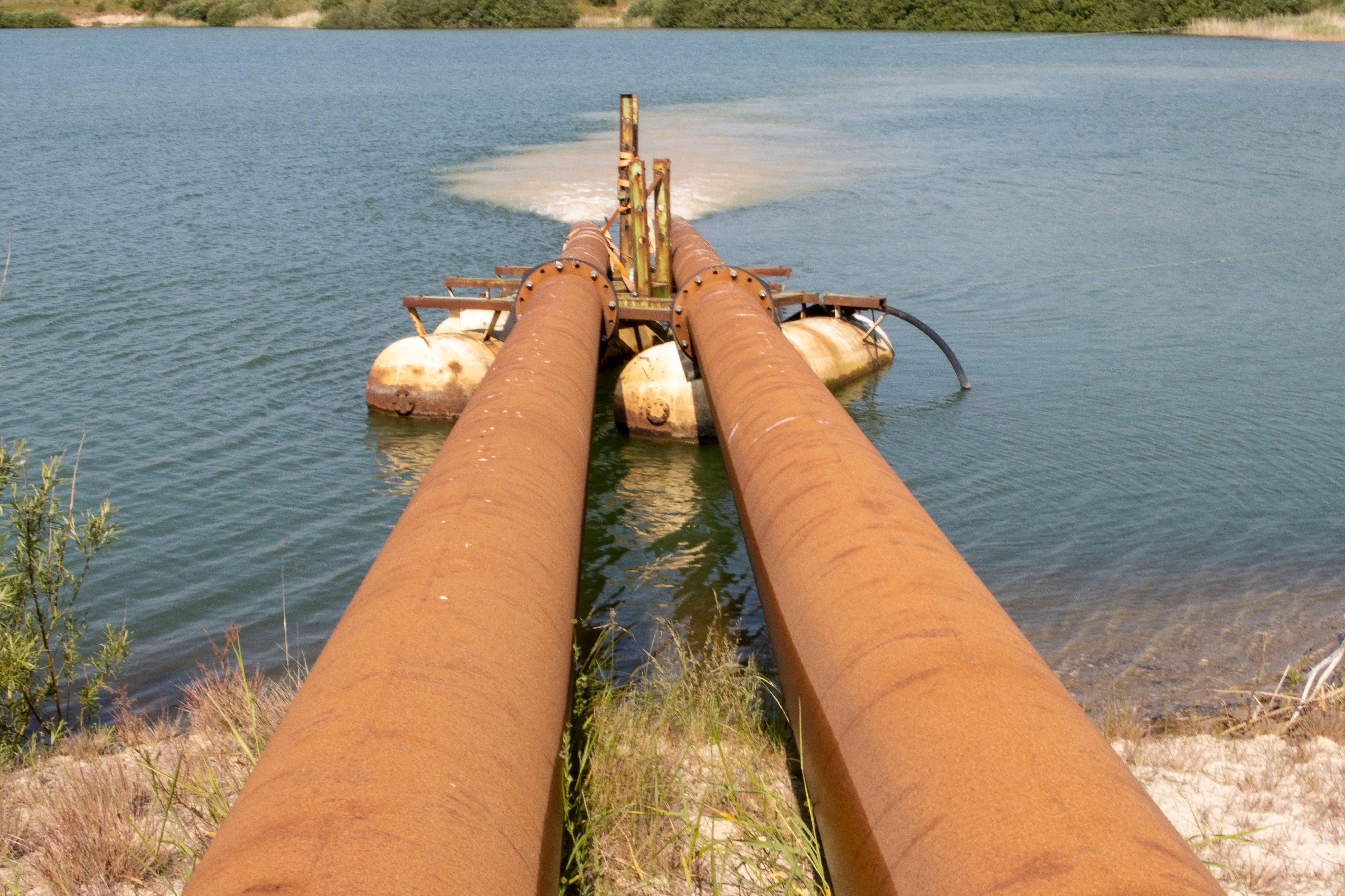 Rust-covered oil pipelines extending over water