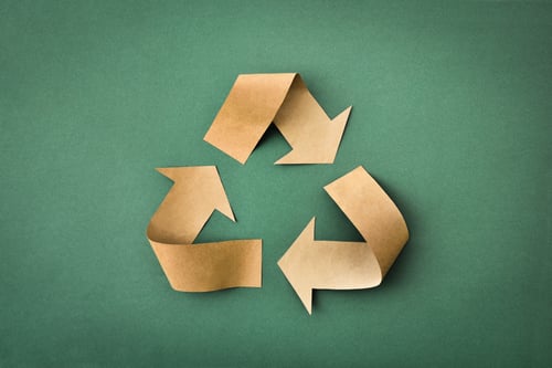 Recycling symbol made of brown paper on green background